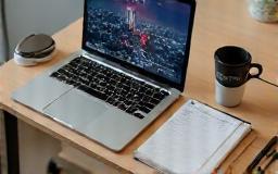 A modern desk setup with a laptop, tablet, and other remote work tools.